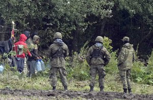 In this Sept. 1, 2021 file photo, migrants stuck along the Poland-Belarus border carry plastic water bottles as they are surrounded by Polish forces in Usnarz Gorny, Poland.