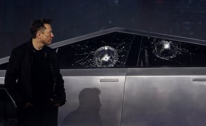 Tesla CEO Elon Musk looks at the broken window glass as he introduces the Cybertruck