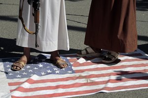 Houthi supporters step and walk on a representation of the U.S. flag during a demonstration outside the closed U.S. embassy against the United States over its decision to designate the Houthis a foreign terrorist organisation in Sanaa, Yemen, Monday, Jan. 18, 2021.