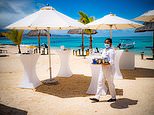 A waitress wears a medical face mask, in accordance with Government guidelines, while clearing beach tables at the Preskill resort in Mauritius (Ben Birchall/PA)