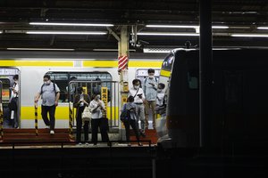 People wearing face masks wait for a train as it approaches at a station in Tokyo, Thursday, Sept. 9, 2021.