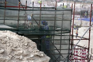 In this May 4, 2015, file photo taken during a government organized media tour, a foreign worker climbs scaffolding at the Al-Wakra Stadium that is under construction for the 2022 World Cup in Doha, Qatar.