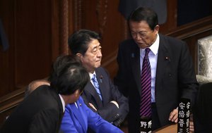 Japanese Prime Minister Shinzo Abe, center, talks with Finance Minister Taro Aso, right, at lower house of the parliament in Tokyo Thursday, Sept. 28, 2017.