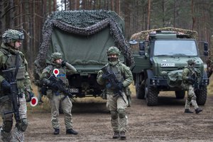 Lithuanian soldiers patrol a road near the Lithuania-Belarus border near the village of Jaskonys, Druskininkai district some 160 km (100 miles) south of the capital Vilnius, Lithuania, Saturday, Nov. 13, 2021