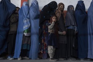 Children and women queue to receive cash at a money distribution organized by the World Food Program in Kabul, Afghanistan, during the World Childen day, on Saturday, Nov. 20, 2021