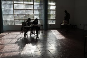 Electoral officials watch as a soldier votes during regional elections at a polling station at the Fermin Toro school in Caracas, Venezuela, Sunday, Nov. 21, 2021.