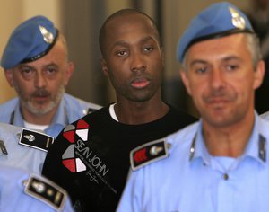 FILE - This Friday, Sept. 26, 2008 file photo shows Rudy Hermann Guede from the Ivory coast, centre, escorted by Italian penitentiary police officers as he leaves Perugia's court after a hearing, central Italy