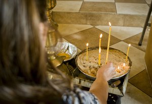 A woman lights candles during a funeral service for victims of a bus crash in Svetovrachene, Bulgaria, Tuesday, Aug. 28, 2018.