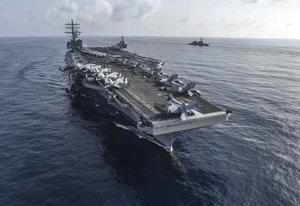 This Aug. 31, 2018, photo released by U.S. Navy, the aircraft carrier USS Ronald Reagan, front, and the guided-missile destroyer USS Milius, center, conduct an exercise with Japan Maritime Self-Defense Force ships off South China Sea.