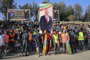 People gather under a placard showing Prime Minister Abiy Ahmed at a rally organized by local authorities to show support for the Ethiopian National Defense Force (ENDF), at Meskel square in downtown Addis Ababa, Ethiopia Sunday, Nov. 7, 2021