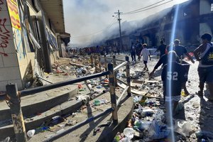 People walk through the looted streets of Chinatown in Honiara, Solomon Islands, Friday, Nov. 26, 2021