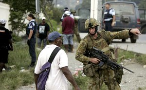 An Australian soldier questions a local in Honiara in the Solomon Islands, Thursday, April 20, 2006, as the town is locked down for the 6 p.m. curfew