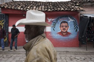 A man walks past a mural of the late Mayor Francisco Gaitan, painted on the facade of the Liberal Party headquarters in Cantarranas, Honduras, Saturday, Nov. 27, 2021, one day ahead of the general elections.