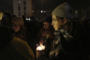 Activists and members of associations defending migrants' rights hold candles next to a banner reading "309 dead on the France UK border since 1999", during a gathering outside the port of Calais, northern France, Thursday, Nov. 25, 2021.