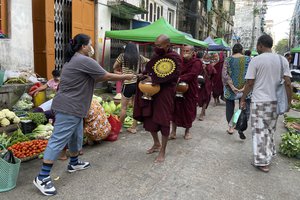 Buddhist monks collect alms from people during their morning walk at the Bogalay Zay Market in Botahtaung township in Yangon, Myanmar on Nov. 12, 2021.