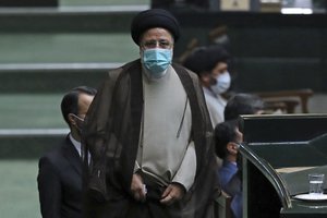 Iranian President Ebrahim Raisi walks towards the podium during a joint session of lawmakers and cabinet members, at the parliament, in Tehran, Iran, Wednesday, Dec. 1, 2021