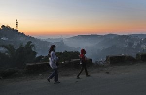 Nagas wearing face masks as a precautionary measure against the coronavirus walk on a road at sunset in Kohima, capital of the northeastern Indian state of Nagaland, Wednesday, Nov. 25, 2020.