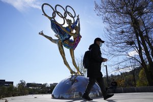 A visitor to the Shougang Park walks past the a sculpture for the Beijing Winter Olympics in Beijing, China, Tuesday, Nov. 9, 2021.