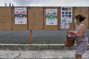 A woman walks past electoral posters calling to vote No to the referendum in Noumea,  New Caledonia, Sunday Dec.12, 2021