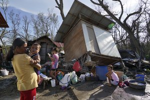 Residents stand beside their damaged homes due to Typhoon Rai in Talisay, Cebu province, central Philippines on Saturday Dec. 18, 2021