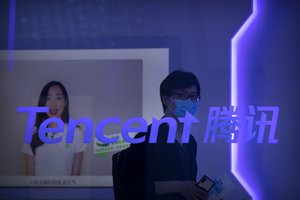 FILE - In this Sept. 5, 2020, file photo, a visitor wearing a face mask walks past a logo for Chinese technology firm Tencent at their display at the China International Fair for Trade in Services (CIFTIS) in Beijing, China