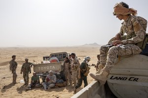 File - Maj. Gen. Nasser al-Dhaibani, who headed military operations of the government's armed forces, fourth from left, holds his beret as he rests with fighters backed by the Saudi-led coalition, near the Kassara frontline with Houthi fighters, near Marib, Yemen, June 20, 2021.