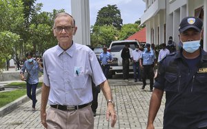 A police officer escorts Richard Daschbach, left, a former missionary from Pennsylvania, U.S. upon his arrival for a trial at a courthouse in Oecusse, East Timor, Tuesday, Feb. 23, 2021