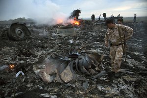 In this July 17, 2014, file photo, people walk amongst the debris at the crash site of a passenger plane near the village of Grabovo, Ukraine