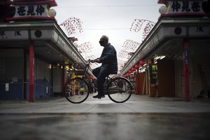 A lone bicyclist cycles through an empty shopping arcade at the Asakusa district in Tokyo Tuesday, Jan. 12, 2021