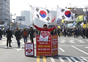 A supporter of South Korean President Park Geun-hye holds the national flags during a rally opposing the parliamentary impeachment of Park in front of the National Assembly in Seoul, South Korea, Friday, Dec. 9, 2016.