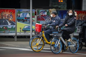 Bicyclists wearing face masks to protect against COVID-19 wait at an intersection in the central business district in Beijing, Thursday, Dec. 23, 2021