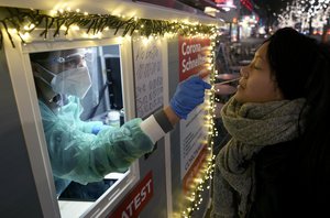 A test center employee performs a coronavirus test in the 'Kurfuerstendamm (Ku'damm)' shopping road in Berlin, Germany, Tuesday, Dec. 21, 2021