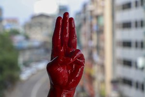 An anti-coup protester shows the three fingered salute and red painted hand in Yangon, Myanmar