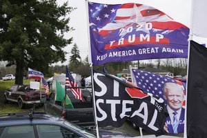 File - Flags supporting President Donald Trump and one that reads "Stop the Steal" are displayed during a protest rally, Jan. 4, 2021, at the Farm Boy Drive-In restaurant near Olympia, Washington.