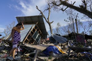 A resident salvages parts of her home damaged due to Typhoon Rai in Talisay, Cebu province, central Philippines on Saturday, Dec. 18, 2021