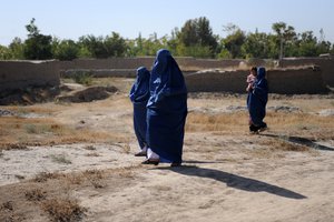 File - Afghan women walk along a road to the village of Talawka, Konduz Province, Afghanistan, Oct. 5, 2010