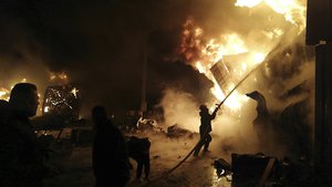 In this photo released by the Syrian official news agency SANA, firefighters work at the scene of missiles attack, at the seaport of the coastal city of Latakia, Syria, Tuesday, Dec. 28, 2021