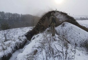 In this image provided by the Ukrainian Board Guard Press Office, Ukrainian border guards watch as a special vehicle digs a trench on the Ukraine-Russia border close to Sumy, Ukraine, Tuesday, Dec. 21, 2021