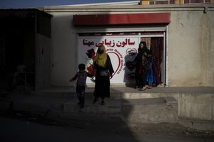 Women and their children exit a beauty saloon in Kabul, Afghanistan, Saturday, Oct. 23, 2021