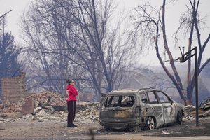 A woman looks at fire damage on Mulberry Street in Louisville, Colo., Friday, Dec. 31, 2021.