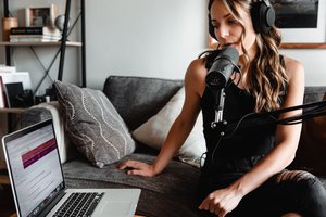 Woman in black tank using Macbook and microphone