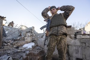 A Ukrainian soldier adjusts his gun near the ruined house at a line of separation from pro-Russian rebels, Donetskregion, Ukraine, Saturday, Jan. 8, 2022.