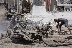 A man sifts through wreckage at the scene of a blast in Mogadishu, Somalia Wednesday, Jan. 12, 2022