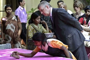 File - Britain’s Prince Andrew, The Duke of York, watches a girl block print a sari during his visit to a child-care home in Ganganagar, near Kolkata, India, Thursday, May 3, 2012.