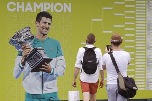 Fans take a photo of defending champion Novak Djokovic of Serbia ahead of first round matches at the Australian Open tennis championships in Melbourne, Australia, Monday, Jan. 17, 2022