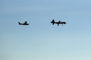 An Unmanned aerial vehicle (drone) General Atomics MQ-9 Reaper remotely piloted aircraft assigned to the 163d Attack Wing and a chase plane circle over March Air Reserve Base, California