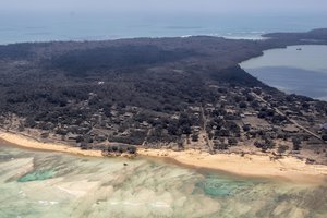 In this photo provided by the New Zealand Defense Force volcanic ash covers roof tops and vegetation in an area of Tonga, Monday, Jan. 17, 2022. Thick ash on an airport runway was delaying aid deliveries to the Pacific island nation of Tonga, where significant damage was being reported days after a huge undersea volcanic eruption and tsunami.