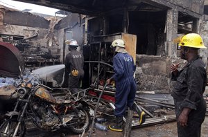 Firefighters spray water over the smoldering remains a gas station following an explosion in Accra, Ghana, Thursday, June 4, 2015.