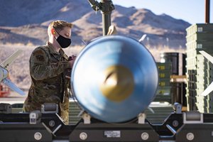 An airman from the 57th Munitions Squadron secures parts of an inert bomb at Nellis Air Force Base, Nevada, Jan. 12, 2022. 57th MUNS Airmen were participating in Iron Flag, a training exercise conducted to build munitions inventory for the base and provide cross-utilization training. The inert bombs that these airmen are producing give fighter pilots the ability to train with munitions without the risks that come with live explosives. (U.S. Air Force photo by Airman Trevor Bell)