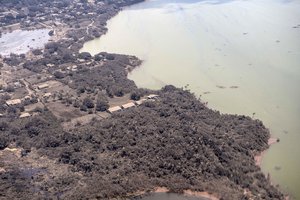 In this photo provided by the New Zealand Defense Force, volcanic ash covers roof tops and vegetation in an area of Tonga, Monday, Jan. 17, 2022